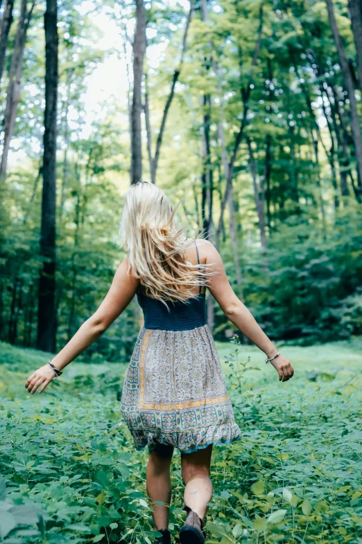 a woman walking through a lush green forest, unsplash, renaissance, flowing blonde hair, arms outstretched, panoramic view of girl, overlooking