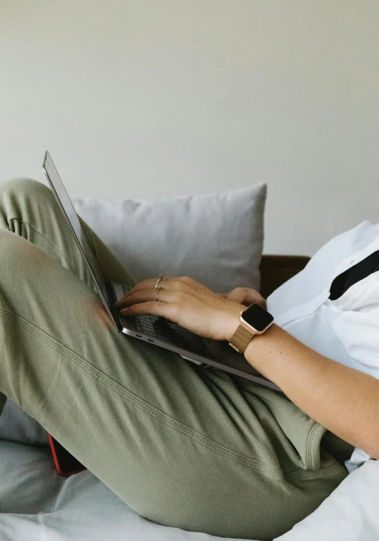 a woman laying on a bed using a laptop computer, trending on pexels, wearing pants and a t-shirt, couch, professional image, profile image