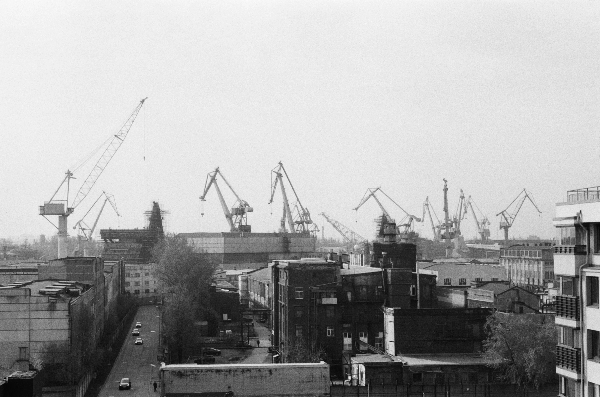 a black and white photo of a city, a black and white photo, flickr, brutalism, shipyard, landscape 35mm veduta photo, cranes, saint petersburg