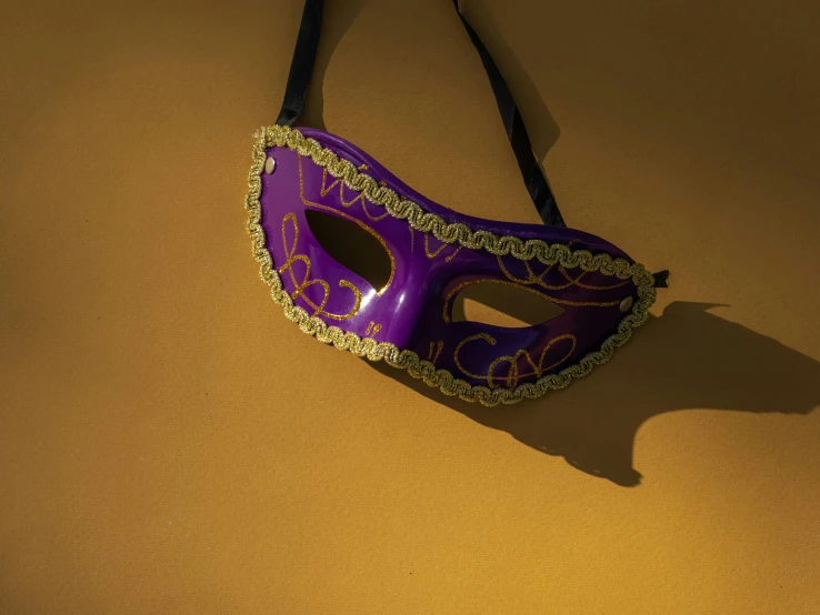 a purple mask hanging on a wall, an album cover, trending on pexels, renaissance, carneval, eye patch, shadow play, golden mask