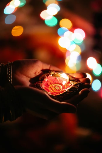 a person holding a lit candle in their hand, hindu ornaments, lots of lights, brightly lit!, holding a flower