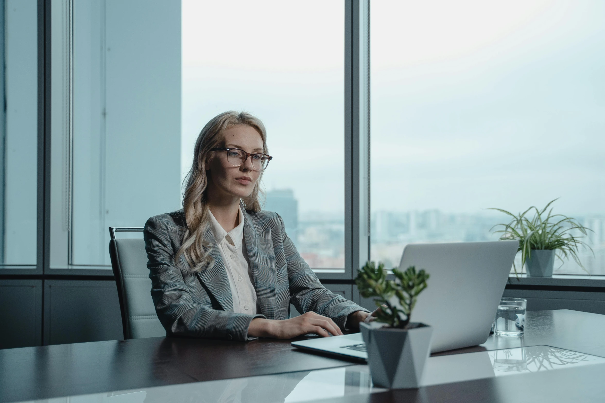 a woman sitting at a table with a laptop, by Emma Andijewska, pexels contest winner, wearing a suit and glasses, avatar image, lachlan bailey, high quality image