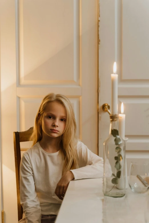 a woman sitting at a table with a candle, a character portrait, by Anna Boch, pexels contest winner, young child, white table, scandinavian style, young teen