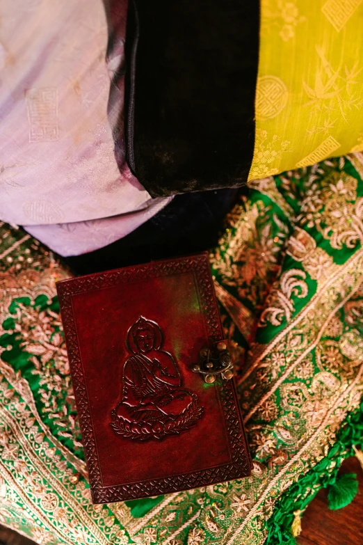 a brown leather wallet sitting on top of a table, cloisonnism, draped in pink and green robes, yantra, - 9