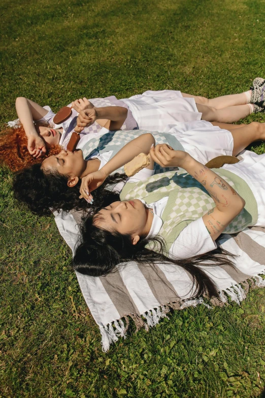 a group of people laying on top of a grass covered field, three women, janice sung, sea - green and white clothes, grimes