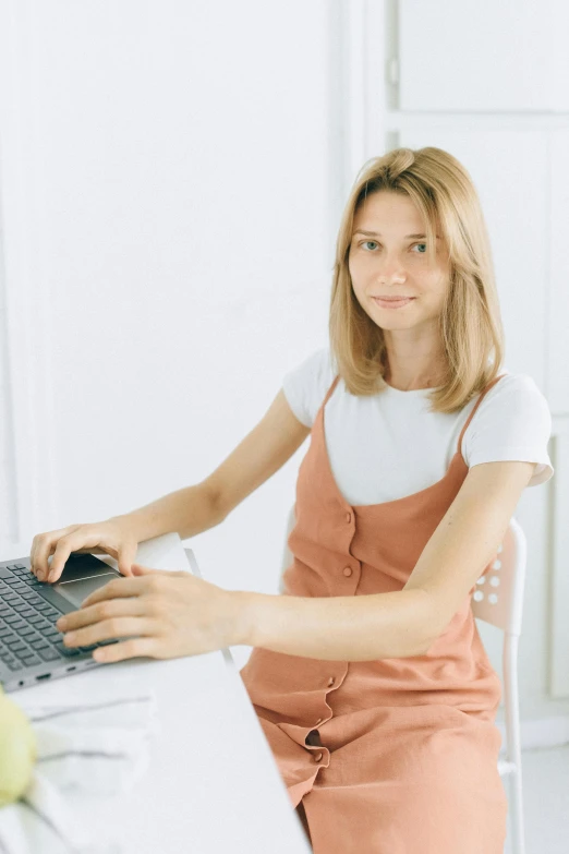 a woman sitting at a desk using a laptop computer, a colorized photo, trending on reddit, wearing a white button up shirt, dasha taran, plain background, avatar image