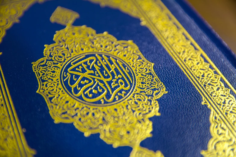 a blue book sitting on top of a wooden table, hurufiyya, highly detailed gold filigree, praise the omnissaiah, intricate embroidery, close - up on detailed