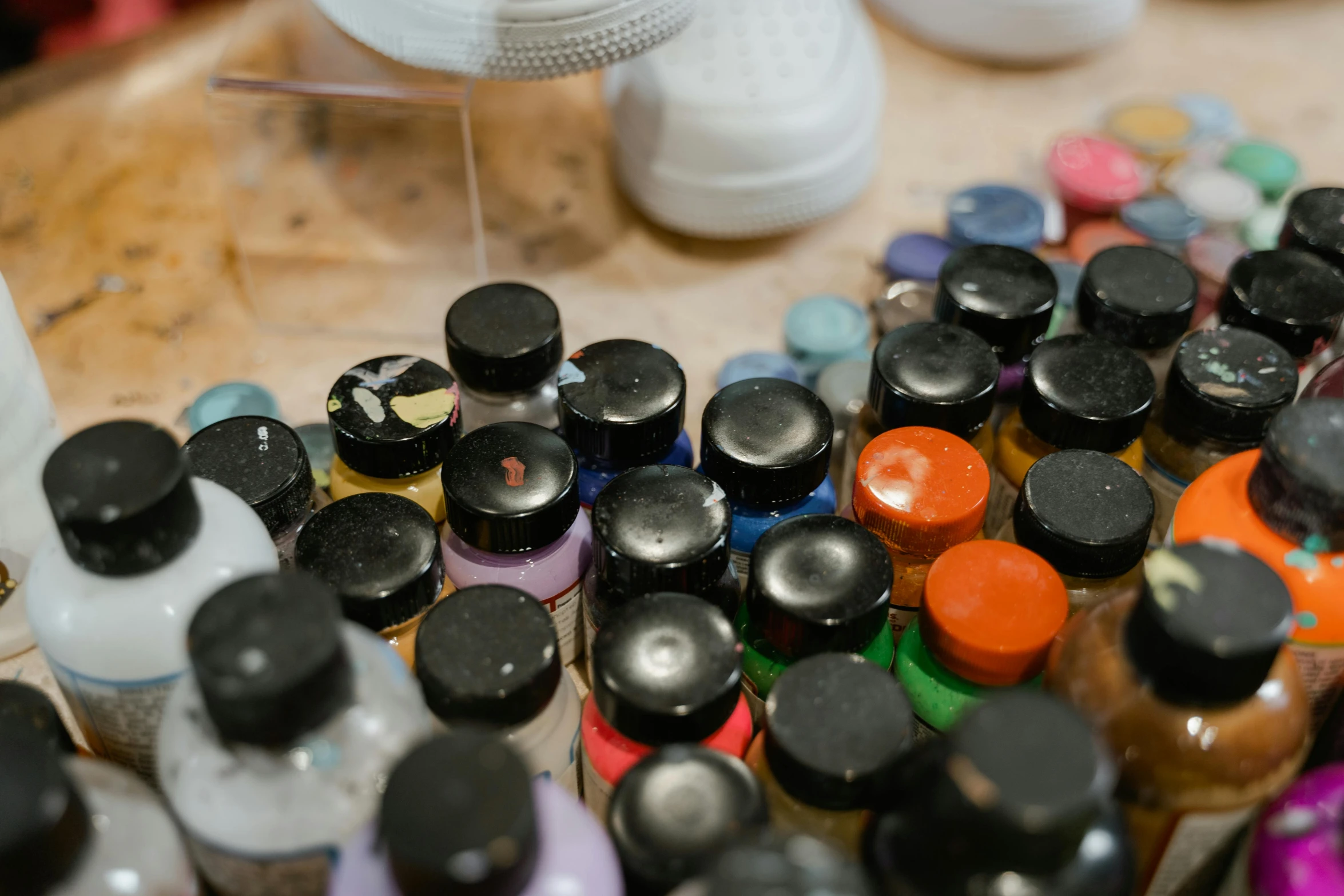 a wooden table topped with lots of bottles of paint, an airbrush painting, unsplash, ink dots, high angle close up shot, tactile buttons and lights, mineral collections