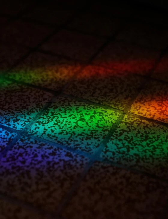 a colorful light shines on a tiled floor, a hologram, trending on unsplash, lgbt, scientific photo, closeup, lgbtq