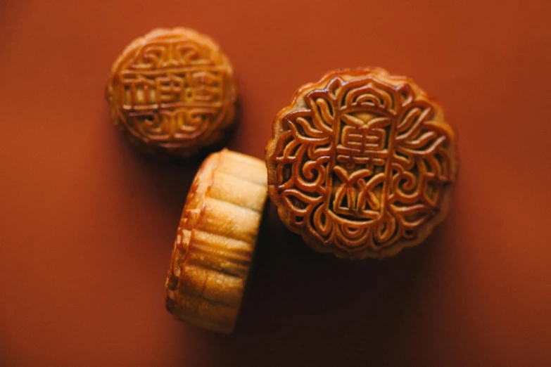 a couple of cookies sitting on top of a table, trending on pexels, hurufiyya, ancient chinese ornate, carved soap, brown, pastry