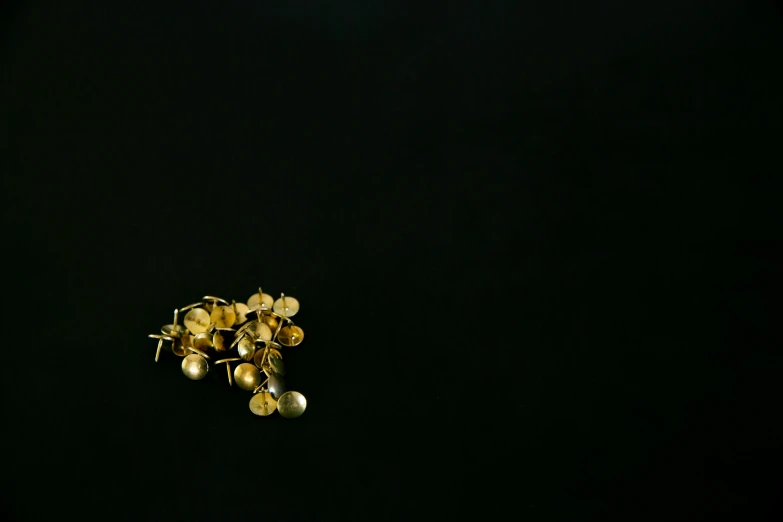 a bunch of gold bells sitting on top of a black surface, by Emma Andijewska, minimalism, earring, spores, akira yasuda, clover