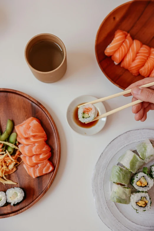 a person holding chopsticks over a plate of sushi, bowl filled with food, salmon, connectivity, daily specials