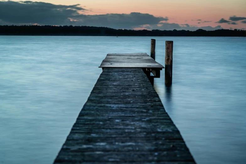 a dock in the middle of a body of water, an album cover, by Peter Churcher, unsplash, serene evening atmosphere, calm evening, inlets