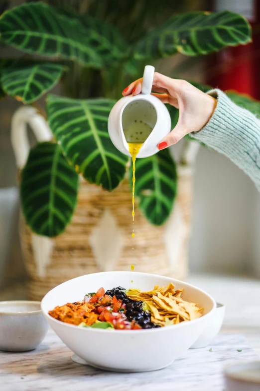 a person pouring syrup onto a bowl of food, by Julia Pishtar, yellow and greens, san francisco, easy to use, olive tree