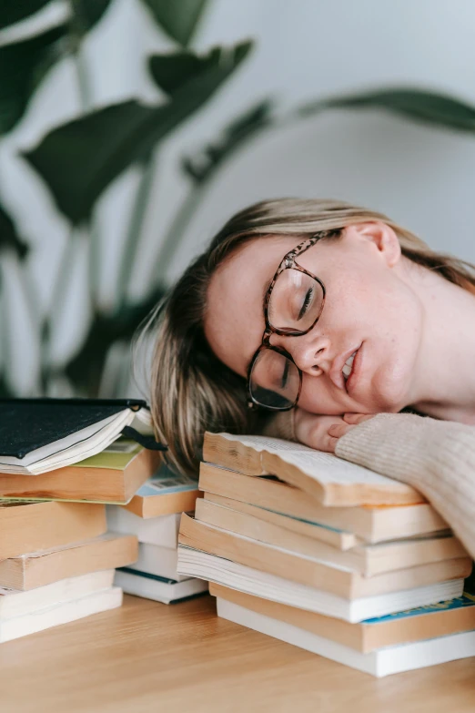 a woman sleeping on top of a pile of books, wearing small round glasses, hungover, featured, highly downvoted