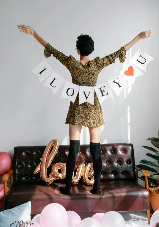 a woman standing on top of a couch in a living room, by Julia Pishtar, featured on instagram, of a ramlethal valentine, trendy typography, cloth banners, i love you