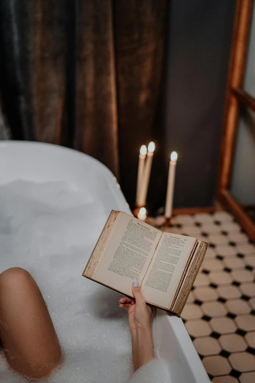 a woman sitting in a bathtub reading a book, inspired by Elsa Bleda, pexels contest winner, romanticism, dripping candles, instagram story, dry brushing, holding books