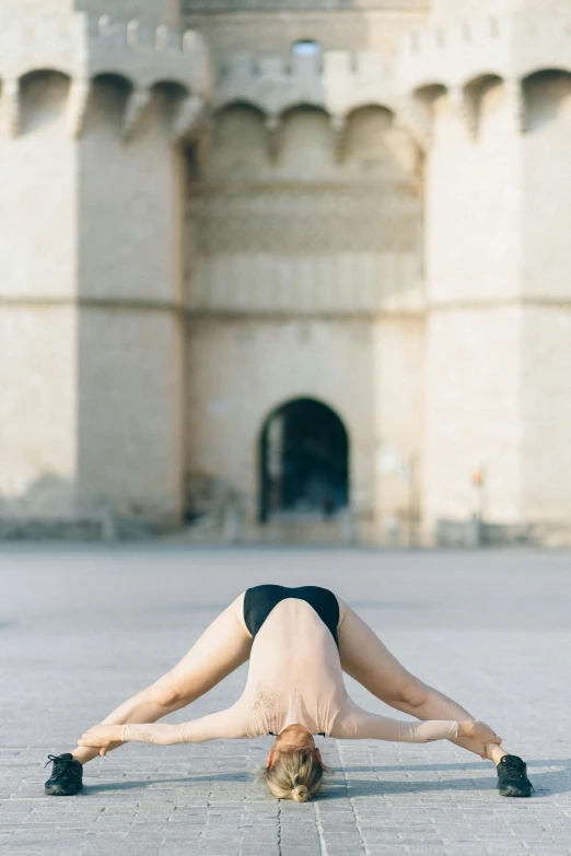 a woman doing a handstand in front of a castle, unsplash, renaissance, in barcelona, lying on the ground, symmetrical detail, arched back