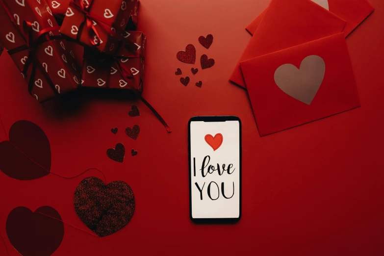 a cell phone sitting on top of a red table, by Julia Pishtar, trending on pexels, hurufiyya, of a ramlethal valentine, i love you, various items, 1 6 9 5