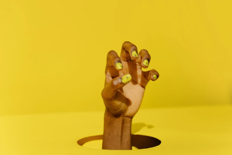 a close up of a person's hand with painted nails, inspired by Russell Dongjun Lu, yellow backdrop, ( ( dark skin ) ), product shoot, banana