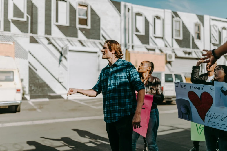 a group of people holding signs in front of a building, by Lee Loughridge, pexels contest winner, visual art, walking through a suburb, man and woman, bo burnham, demo scene