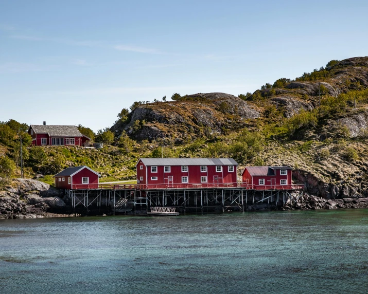 a red house sitting on top of a hill next to a body of water, by Jesper Knudsen, pexels contest winner, hurufiyya, several cottages, archipelago, conde nast traveler photo, docks