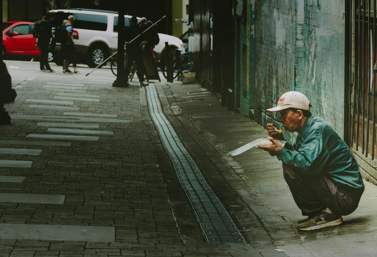 a man kneeling down with a knife in his hand, by Gang Hui-an, pexels contest winner, street art, vhs colour photography, panoramic anamorphic, smoking a pipe, green alleys