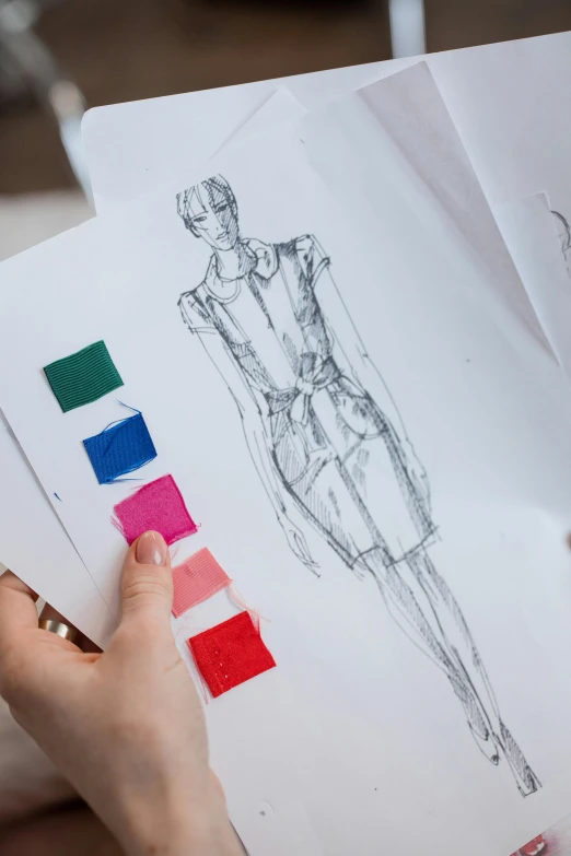 a person holding a piece of paper with a drawing on it, fashion design, solid colours material, thumbnail