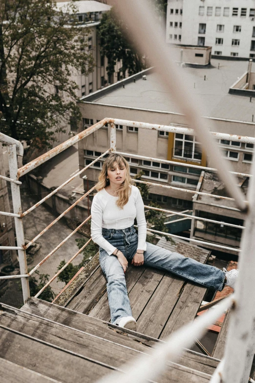 a woman sitting on top of a wooden staircase, inspired by Elsa Bleda, trending on pexels, happening, standing on rooftop, portrait of kim petras, anna nikonova aka newmilky, jeans