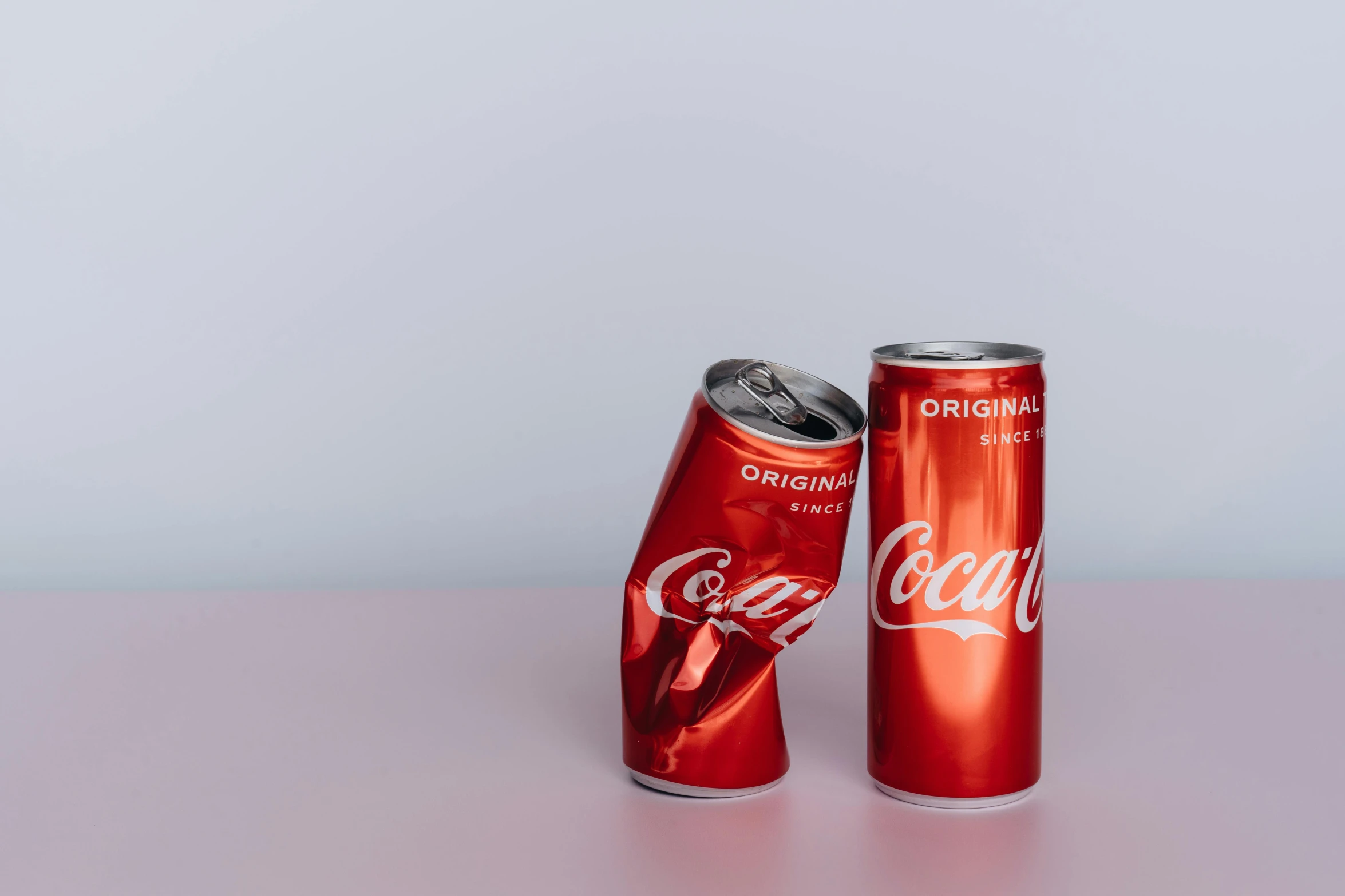 two coke cans sitting next to each other on a table, trending on unsplash, plain background, collapsing, adult pair of twins, metallic red