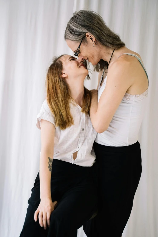 a couple of women standing next to each other, unsplash, lesbian embrace, white backdrop, straya, soft lulling tongue