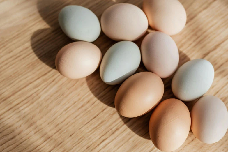 a pile of eggs sitting on top of a wooden table, pastel colours, daily specials, thumbnail, hybrids