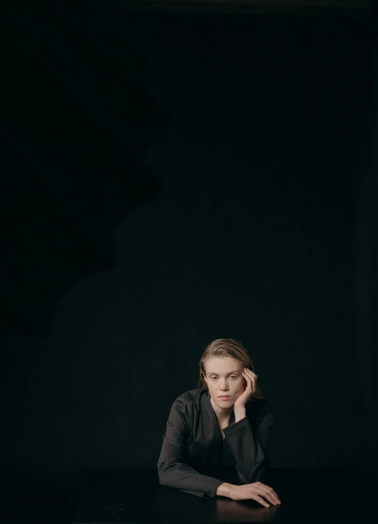 a woman sitting at a table in a dark room, a portrait, by Emma Andijewska, minimalism, elize theron, ansel ], low quality photo, zellk