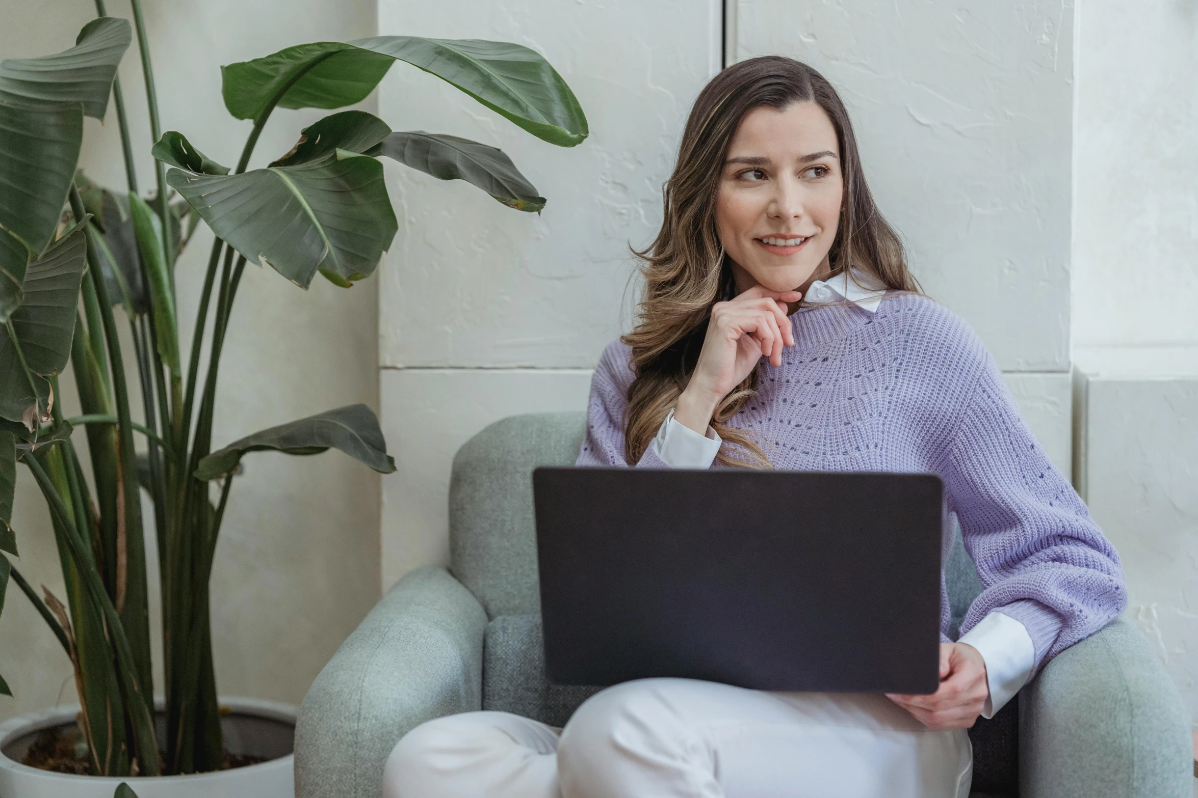 a woman sitting in a chair with a laptop, a portrait, trending on pexels, subtle purple accents, next to a plant, it specialist, woman with braided brown hair