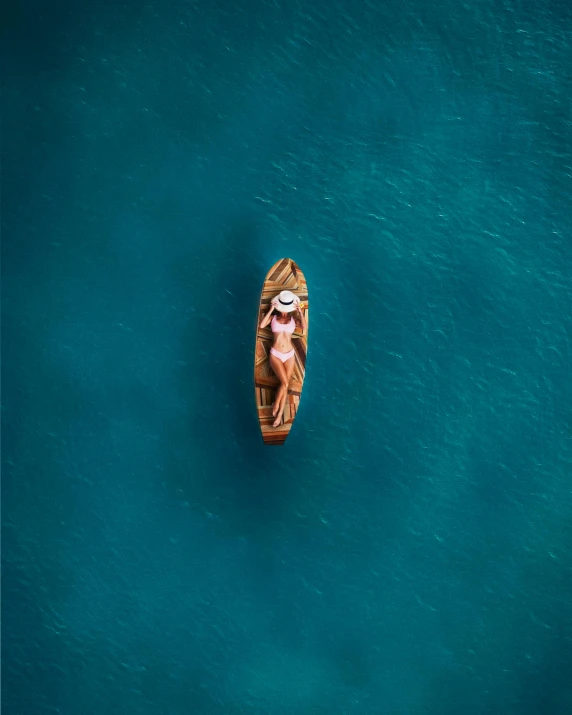 a small boat floating on top of a body of water, by Sebastian Spreng, unsplash contest winner, brown and cyan blue color scheme, cute woman, drone photo, conde nast traveler photo