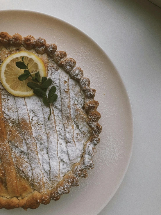 a white plate topped with a pie covered in powdered sugar, by Robbie Trevino, trending on unsplash, lemon, 2 5 6 x 2 5 6 pixels, 🚿🗝📝