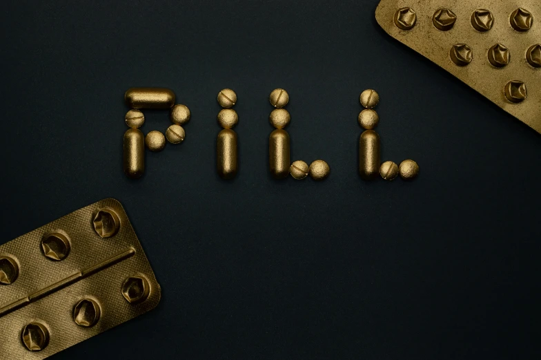 a couple of pills sitting on top of a table, a still life, by Julia Pishtar, unsplash, surrealism, detailed letters, made of gold, bolts, detailed product image