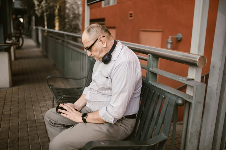 a man sitting on a bench using a cell phone, wearing a headset, sean mcloughlin, depressing image, profile image