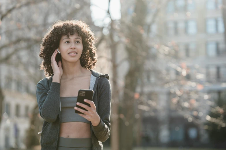 a woman talking on a cell phone in a park, by Adam Marczyński, trending on pexels, happening, wearing fitness gear, curly haired, avatar image, hyperdetailed