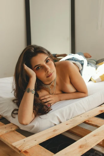a woman laying on top of a wooden pallet, a portrait, inspired by Elsa Bleda, trending on pexels, alone gorgeous latin woman, on the bed, gif, attractive photo