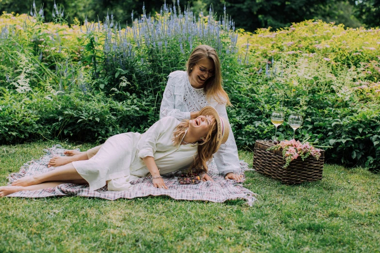 a woman sitting on top of a lush green field, by Alice Mason, pexels contest winner, woman holding another woman, bed of flowers on floor, wine, midsommar - t