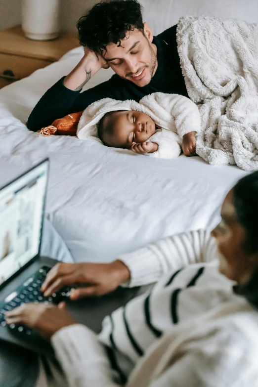 a man and woman laying on a bed with a baby, pexels contest winner, renaissance, working on her laptop, diverse, future tech, profile image