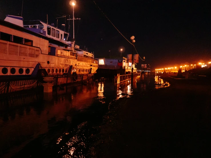 a couple of boats that are sitting in the water, by Jan Tengnagel, pexels contest winner, hurufiyya, taverns nighttime lifestyle, shipping docks, thumbnail, night time footage