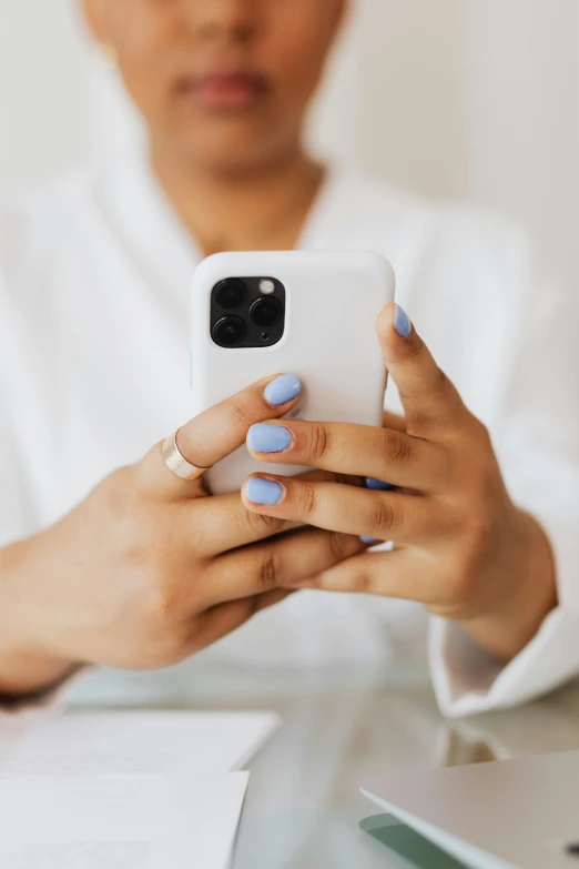 a close up of a person holding a cell phone, trending on pexels, white and pale blue, partially cupping her hands, manicured, cover story