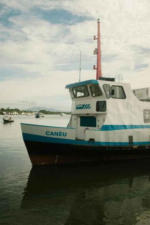 a blue and white boat sitting on top of a body of water, an album cover, by Camille-Pierre Pambu Bodo, docked at harbor, waneella, canopee, utilitarian cargo ship