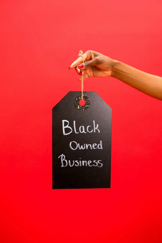 a woman holding a sign that says black owned business, an album cover, pexels, black on red, square, vantablack gi, business attire