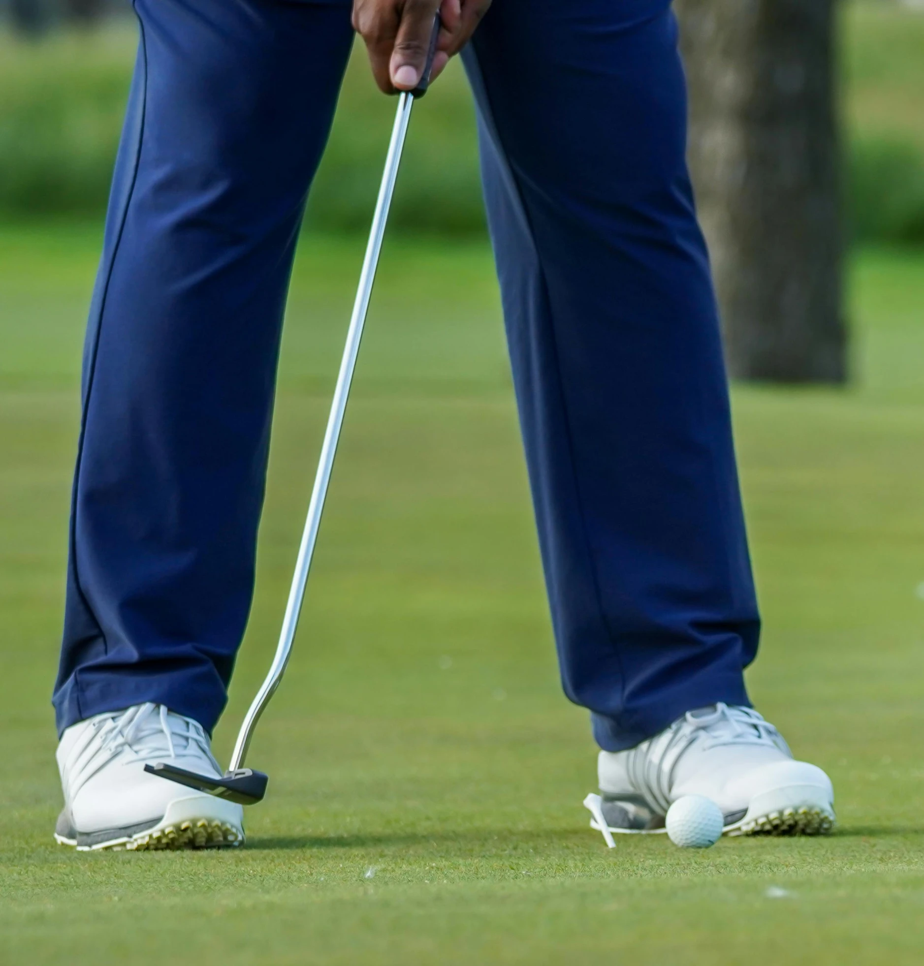 a man holding a golf club on top of a green field, the forefoot to make a v gesture, off - putting, large pants, tournament