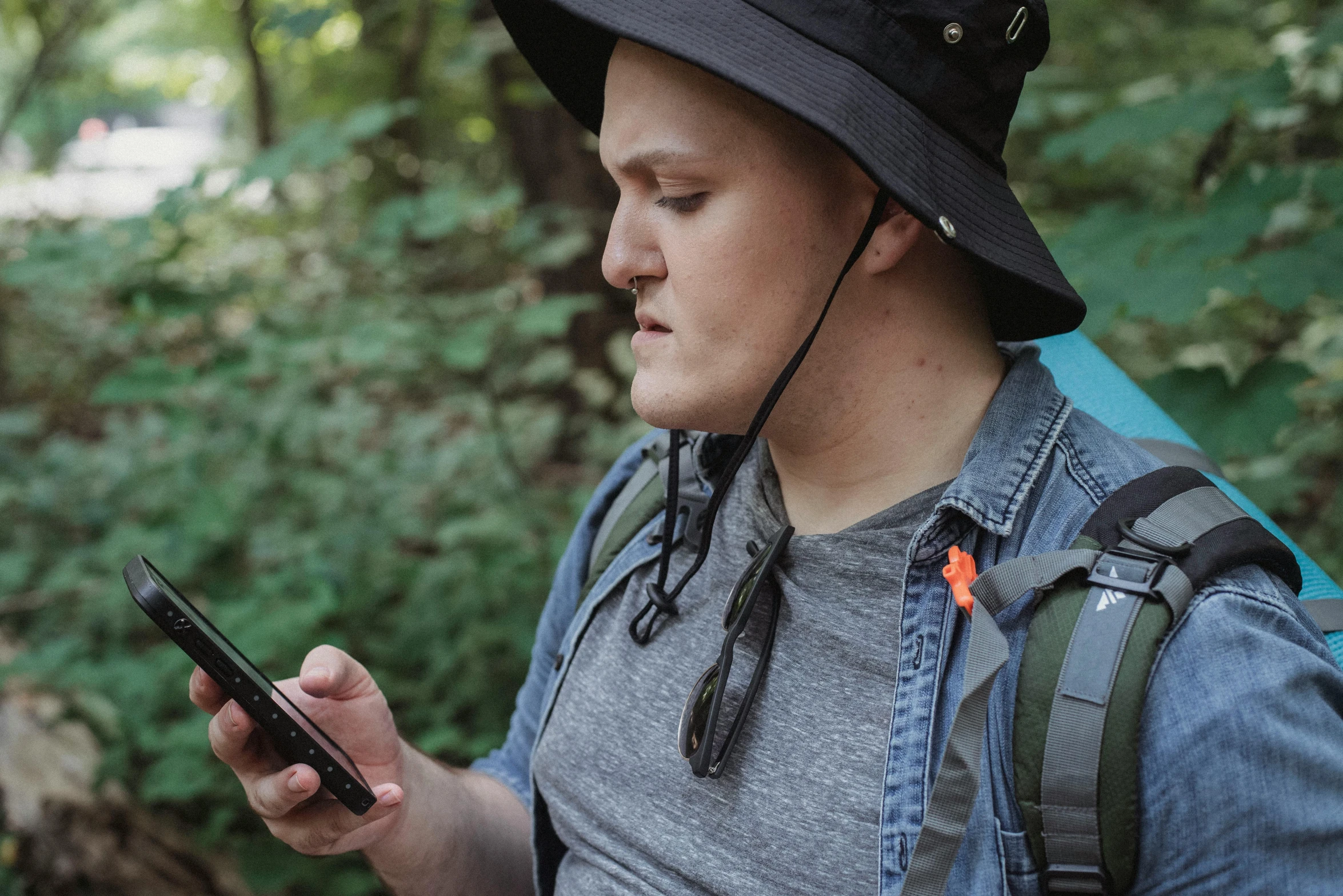 a man in a hat looking at his cell phone, by Meredith Dillman, pexels, trekking in a forest, wearing a gaming headset, avatar image, college