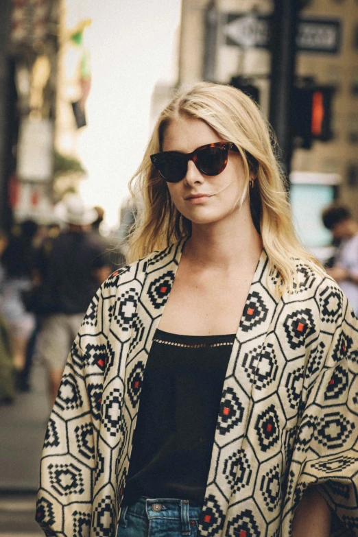 a woman in sunglasses is walking down the street, by Nina Hamnett, trending on unsplash, patterned clothing, gorgeous female samara weaving, elegant cape, in new york