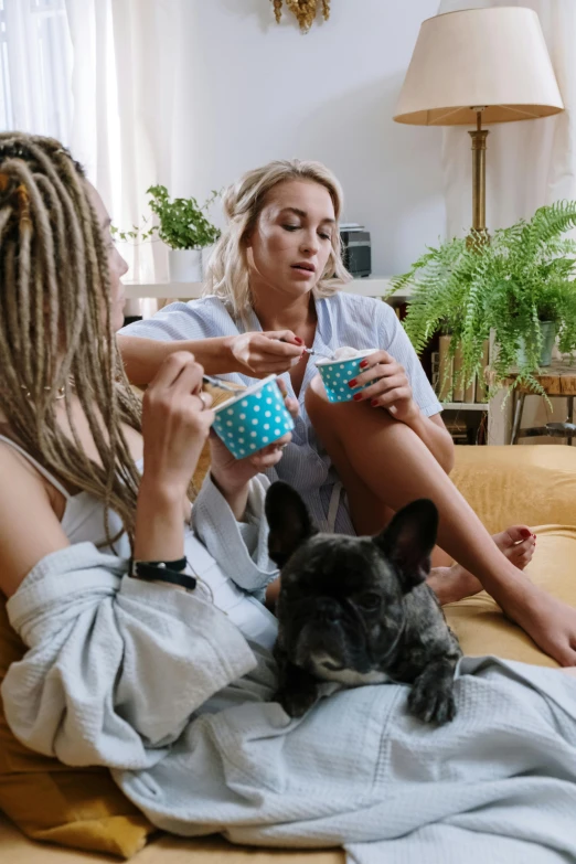 a couple of women sitting on top of a couch next to a dog, trending on pexels, renaissance, two cups of coffee, blonde, smoking a bowl of hash together, gif